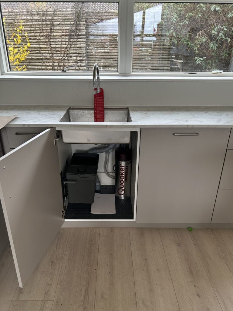 Moderne køkkenvask med åbent skab og Quooker system