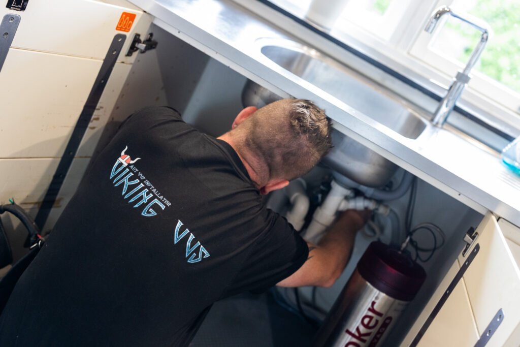 VVS-installatør reparerer rør under køkkenvask