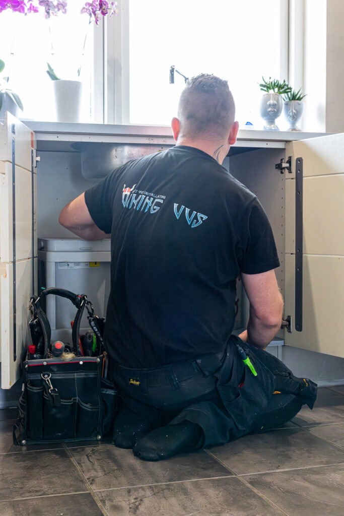 VVS-installatør reparerer vandrør under køkkenvask