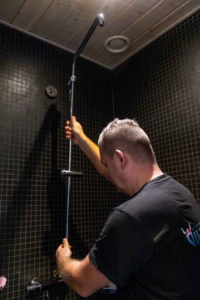 Mand installerer bruser på badeværelse