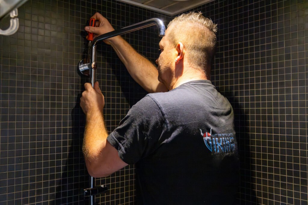 VVS-montør reparerer brusearmatur på badeværelse