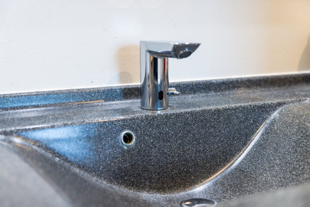 Moderne berøringsfri vandhane på grå vask