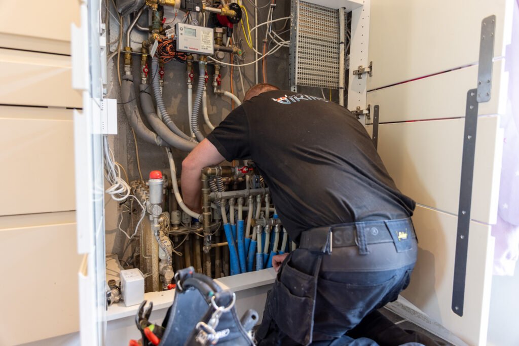 VVS-installatør reparerer rør i teknikskab