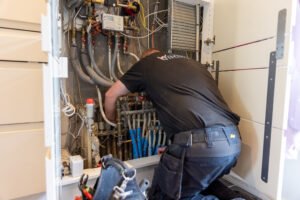 VVS-installatør reparerer rør i teknikskab