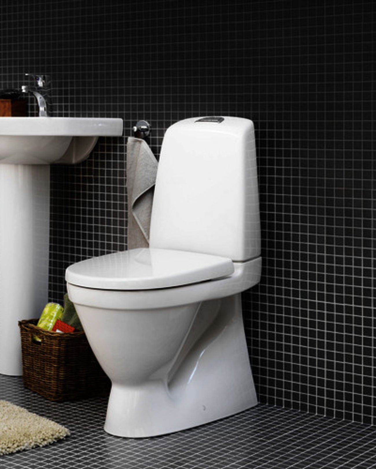 Hvid toilet i moderne badeværelse med sort flisevæg