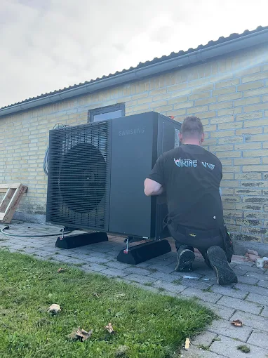 Tekniker installerer varmepumpe ved et hus